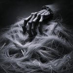 Dramatic, black and white image of a skeletal, gnarled hand with long fingers reaching into a large pile of straw. The hand emerges from a dark sleeve, suggesting a mysterious and menacing presence, symbolising the Rumpelstiltskin fable and the dangers of impossible demands.